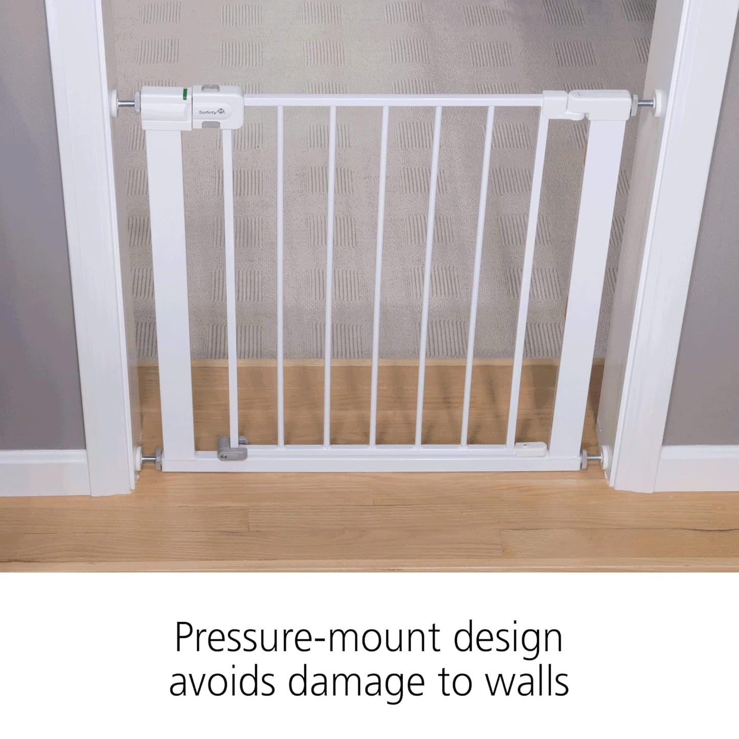White pressure-mount baby gate on a wooden floor with text indicating it avoids wall damage.
