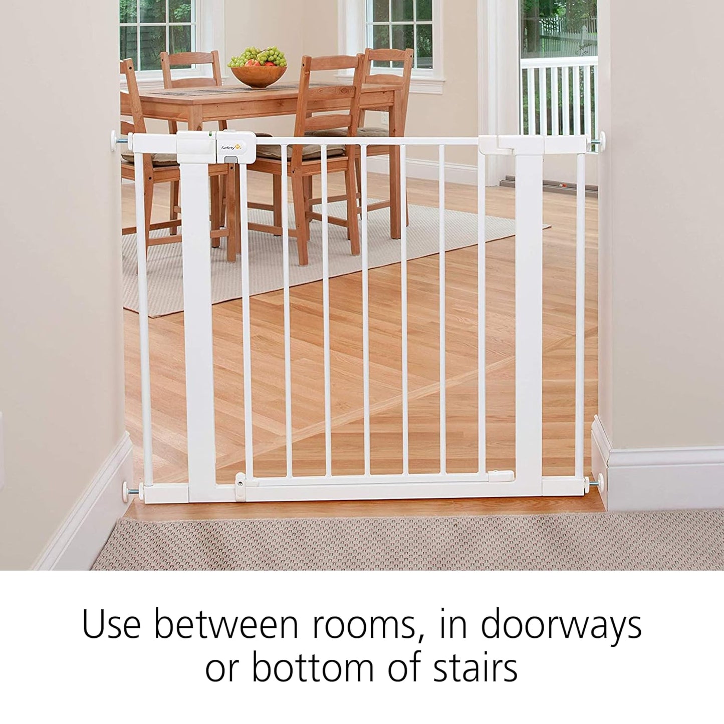 White baby gate in a home setting with a dining table and chairs in the background.